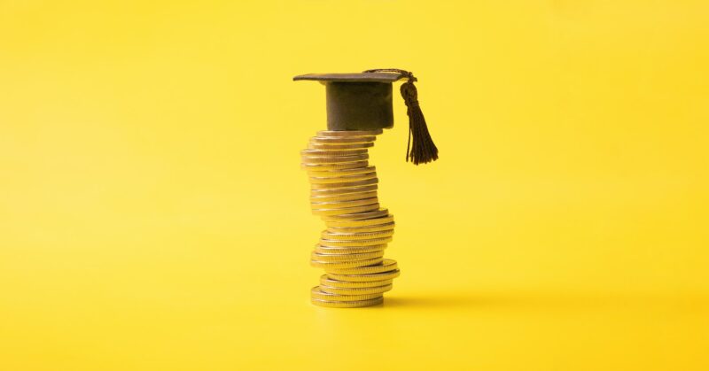 Graduated cap with coins on yellow background. Savings for education concept