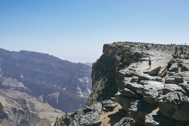 Grand Canyon of Oman. Tourist walking on the edge of cliff. Mountain range Jebel Akhdar.
