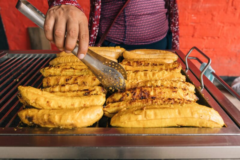 Grilling sweet plantains at a street market stall an unrecognizable person