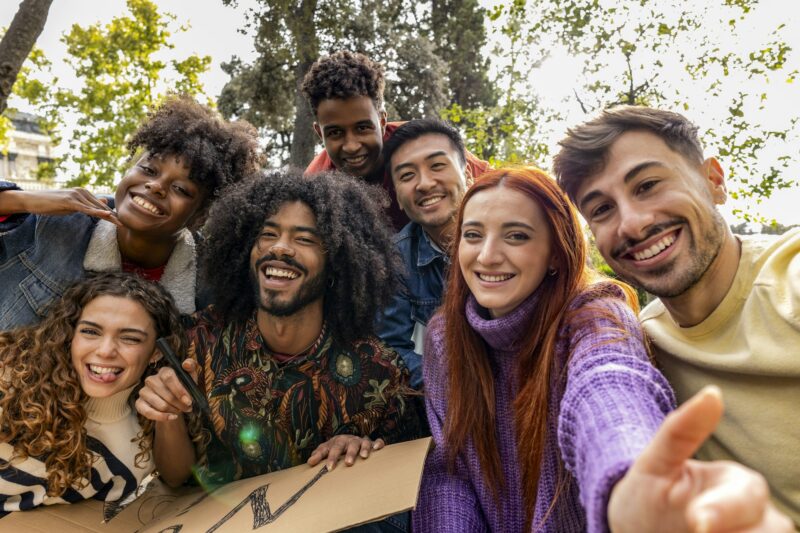 group of smiling multiracial teenage friends taking selfies during a peace march
