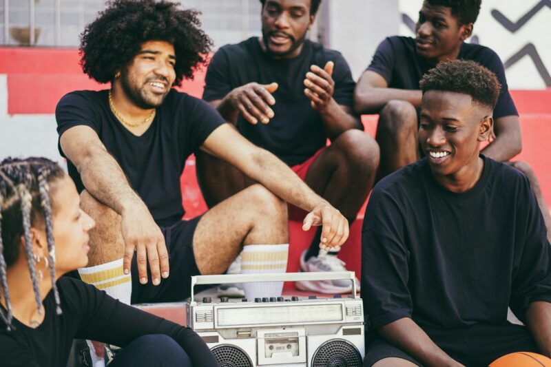 Group of young african people listening music outdoor after basketball match