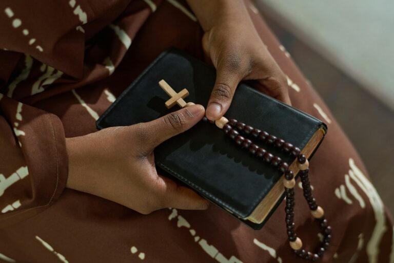 Hands of young African American parishioner of catholic church holding Bible