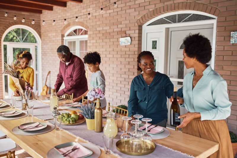 Happy African American people enjoying in setting dining table for family meal on a patio.