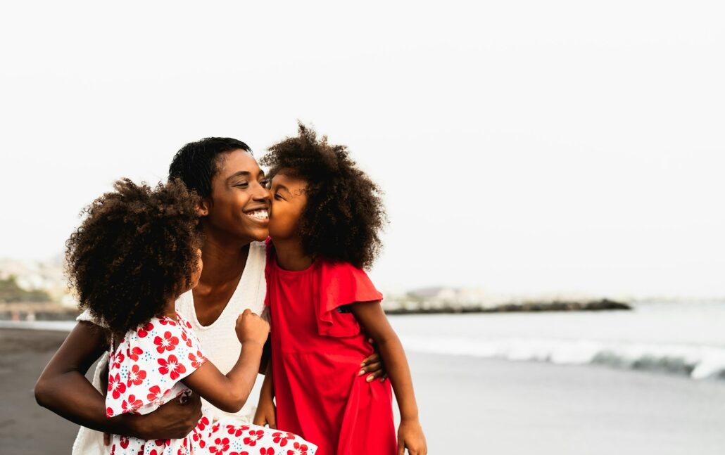 Happy African family having fun on the beach during summer vacations