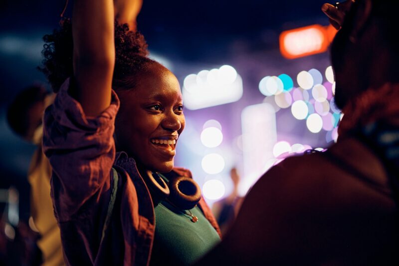 Happy black woman having fun while attending open air music festival at night.