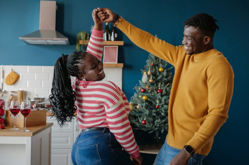 Happy young African couple dancing and smiling while celebrating Christmas at home together