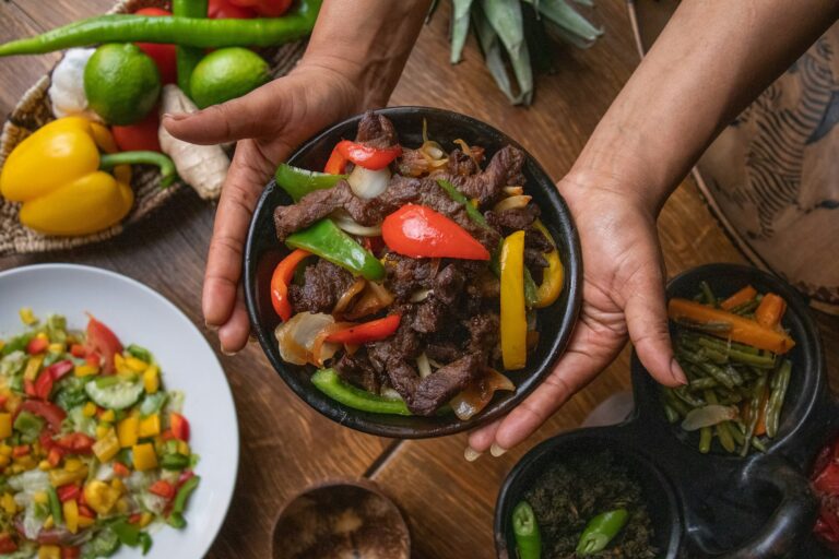 High angle shot of a person holding a plate of Ethiopian food with vegetables on a wooden table