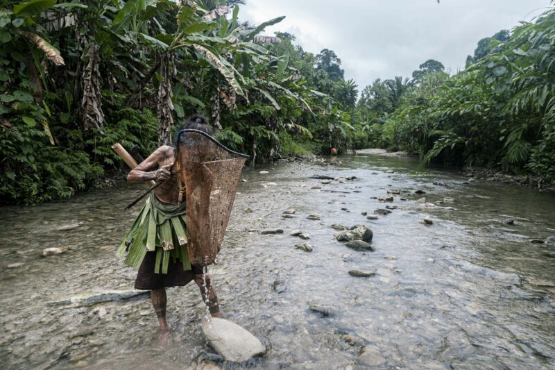 Indigenous man standing in river stream of amazon
