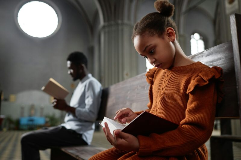 Little girl reading Bible in church