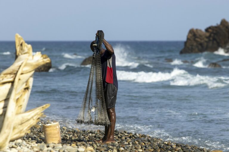 man standing on beach by shore and holding net in his hands