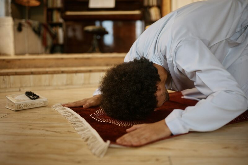 Middle Eastern man in traditional prayer pose at home.
