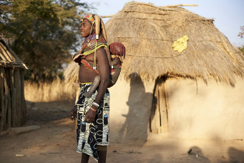Muhila tribe woman carrying her child on her back, Kehamba, Chibia, Angola