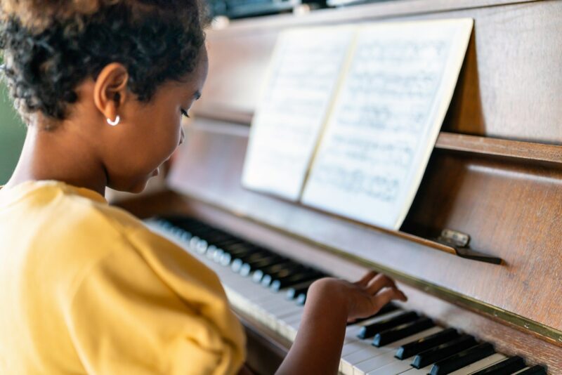 Musical education. Happy black girl playing the piano