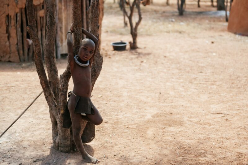 Namibia, Africa - June 14, 2021: Standing near tree. Child of the ethnic people of Africa