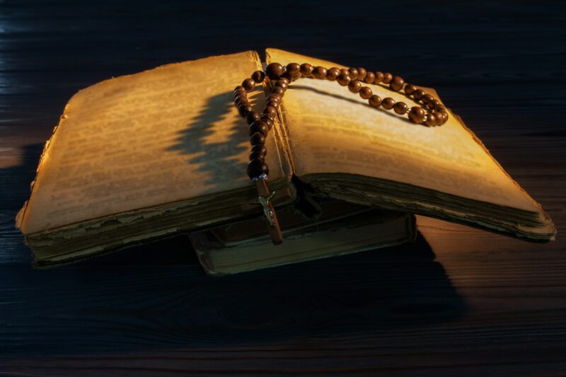 Old open bible with rosary beads.