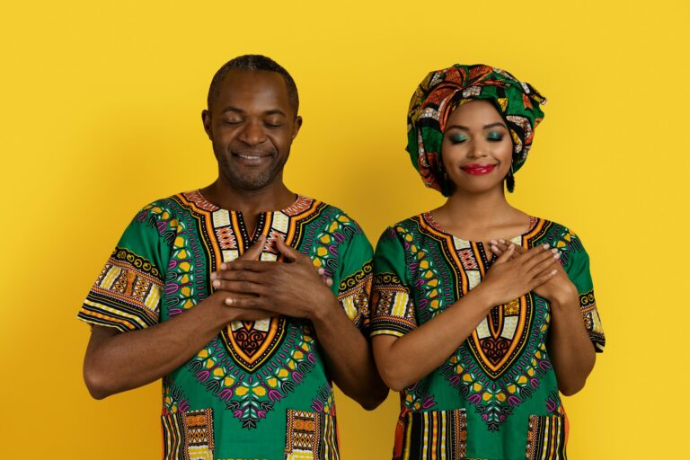 Peaceful african lovers in traditional costumes holding hands on chest