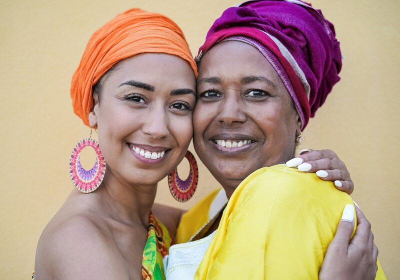 Portrait of happy african mother and adult daughter wearing traditional dress and turban