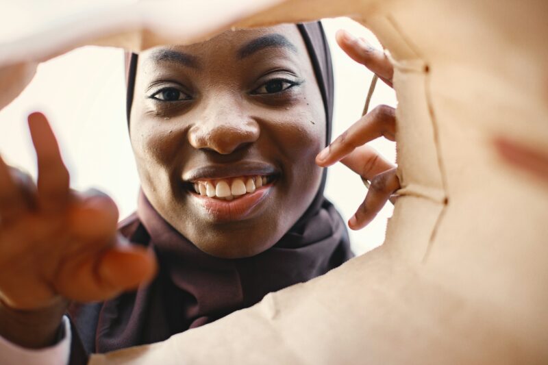 Portrait of young muslim woman wearing hijab looking inside bag