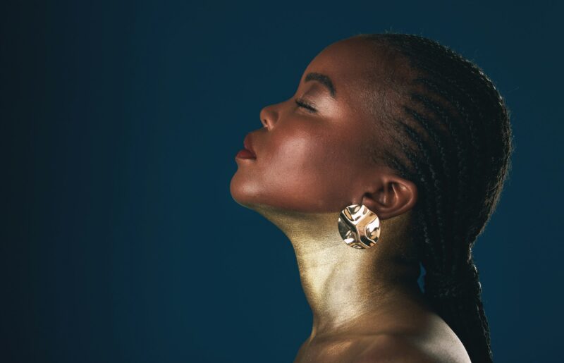 Profile, beauty and black woman in gold for culture, heritage or tradition on a blue background in