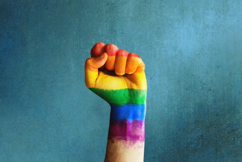 Raised rainbow fist of a man for PRIDE month and the LGBTQIA+ movement