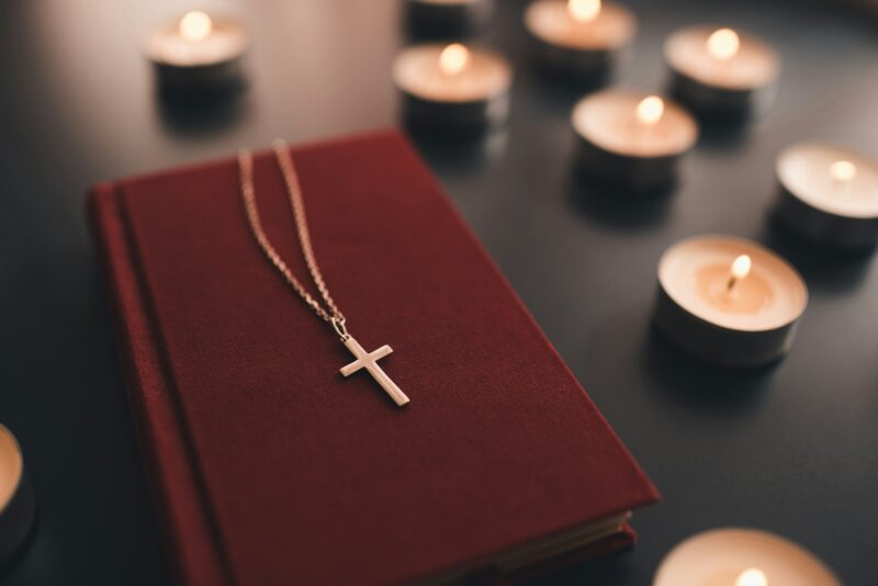 Religious cross on bible with candles