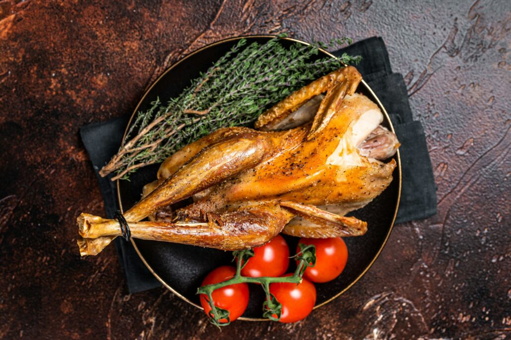 Roast guinea fowl with herbs and spices, cooked game bird. Dark background. Top view