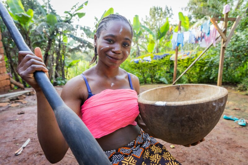 Smiling young African villager lady ready to pound some carbohydrate for her family meal