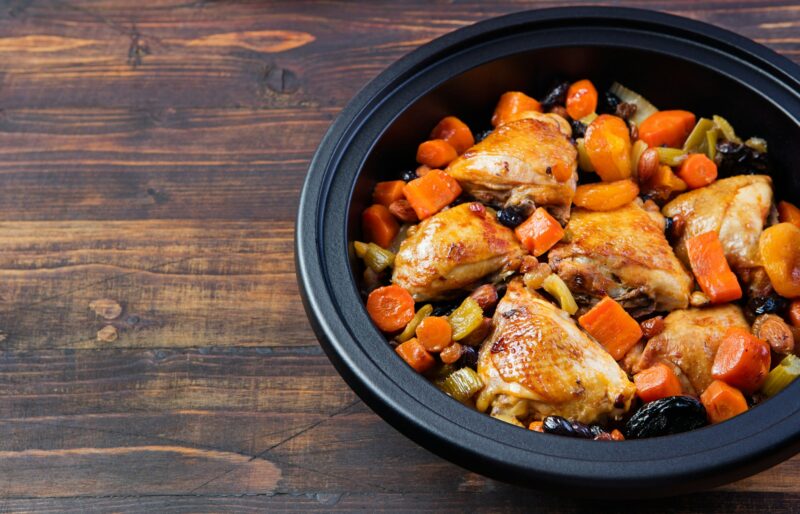 Tagine with cooked chicken and vegetables. Traditional moroccan cuisine. Wooden background Copy