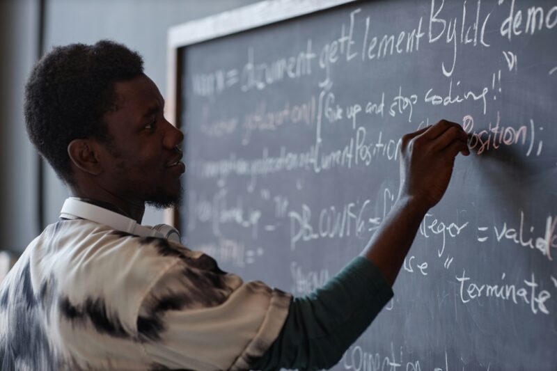 Teacher writing on blackboard in the classroom