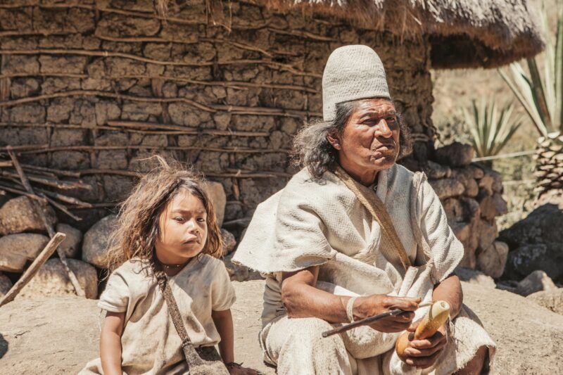 The grandfather and grandson of an indigenous family pose in front in their traditional costume