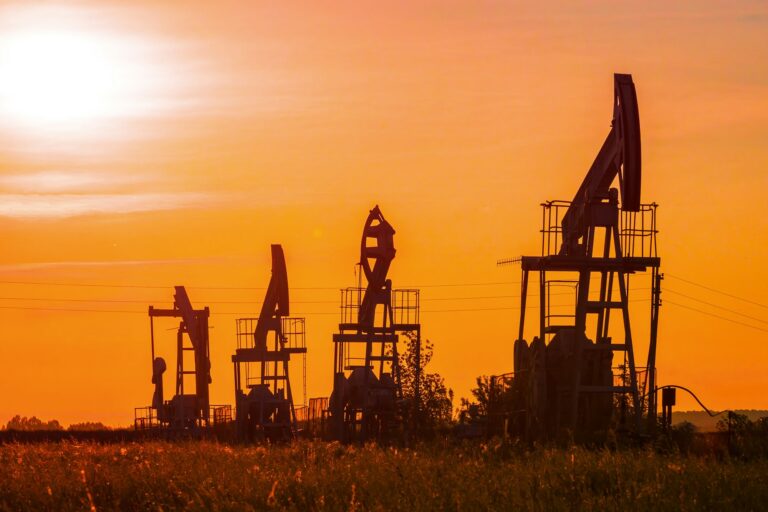 The silhouette of oil pumps in a large oil field at sunrise.