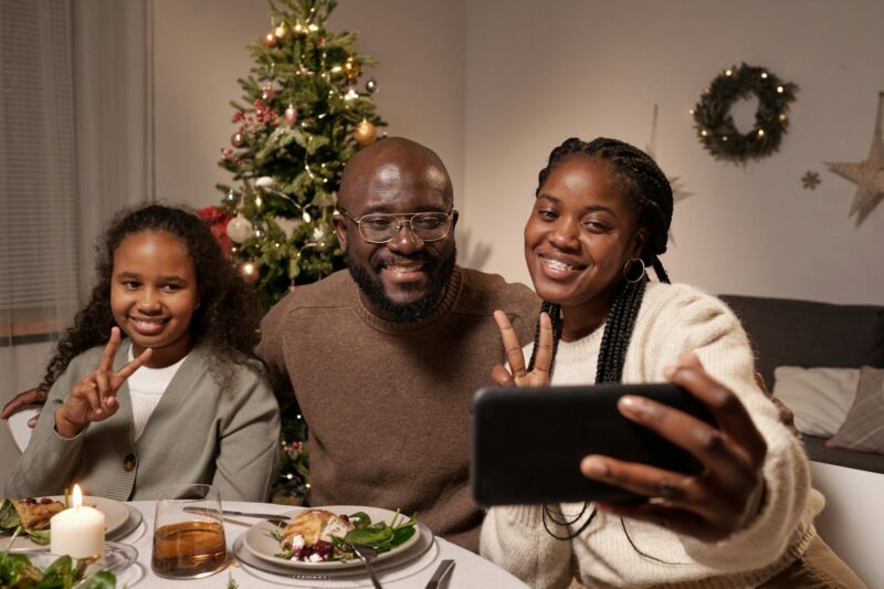 Three African people making selfie by festive table on xmas day