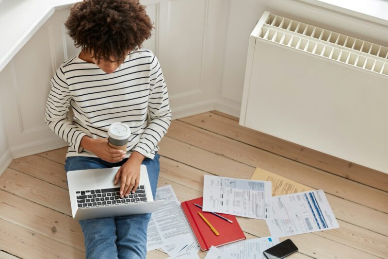 Top view of busy experienced distant worker keyboards on laptop computer, calculates costs, makes re