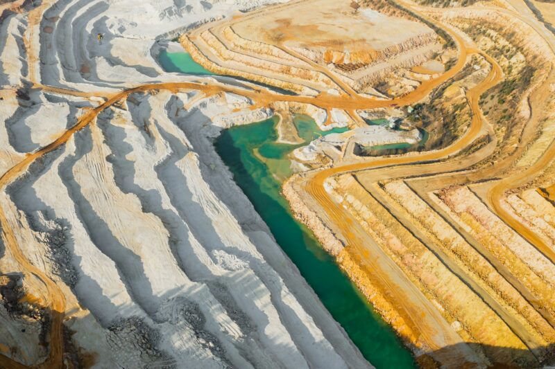 Top view on a sand quarry. Arial view on a mining of natural resources or ore. Green river separates