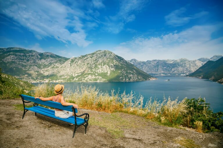 Tourist woman resting on a bench in the romantic spot in mountains in the Bay of Kotor