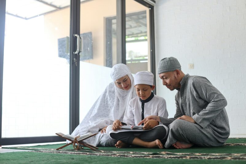 Traditional muslim family reading Quran and praying together
