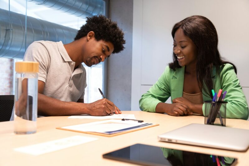 Two african american people signing contract in office.