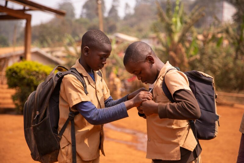 Two african children with their heavy backpacks play in the school yard