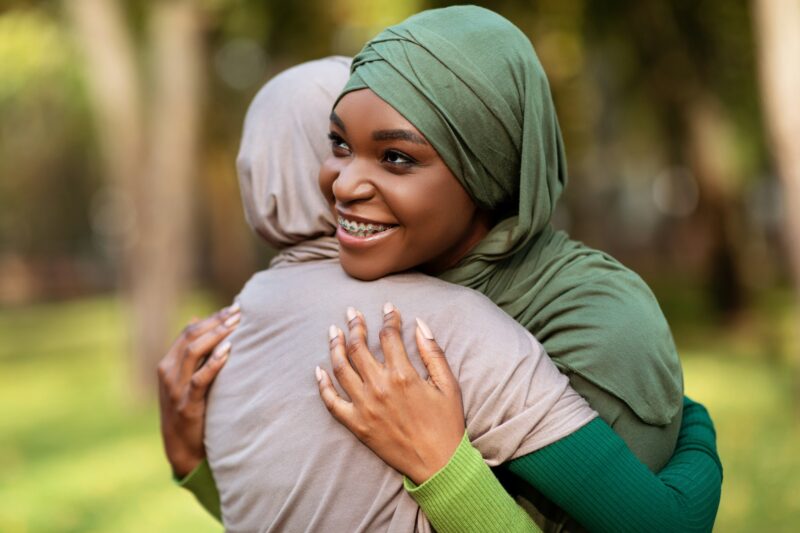 Two Diverse Islamic Ladies Embracing Standing In Park Outside