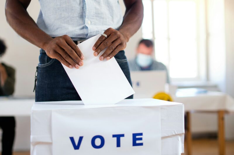 Unrecognizable african-american man putting his vote in the ballot box, usa elections and