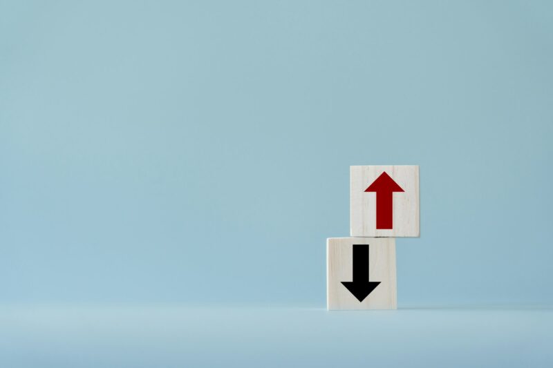 Up and down turn arrow on wooden blocks difference direction to earn or to loss