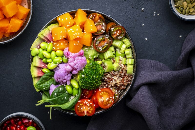 Vegan buddha bowl with pumpkin, quinoa, tomatoes, spinach, edamame, tofu, cauliflower, broccoli