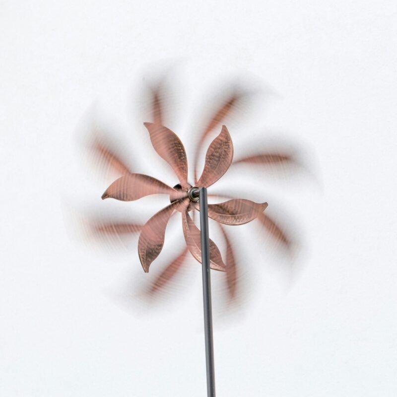 Vibrant pink metal wind spinner suspended in front of a stark white background