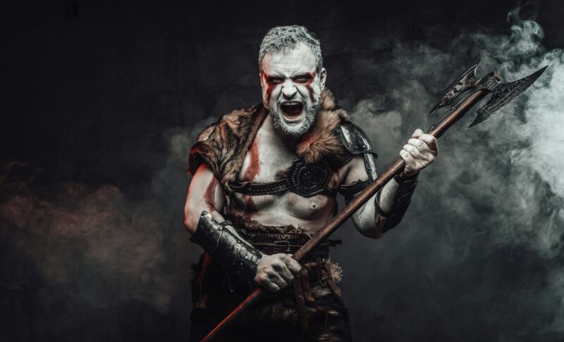 Violent and savage fighter with axe in dark smokey background