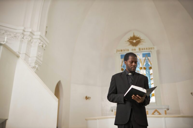 Wide Angle African American Priest Reading Bible at Church Altar