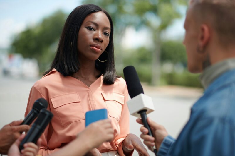 Woman Answering Questions of Journalists