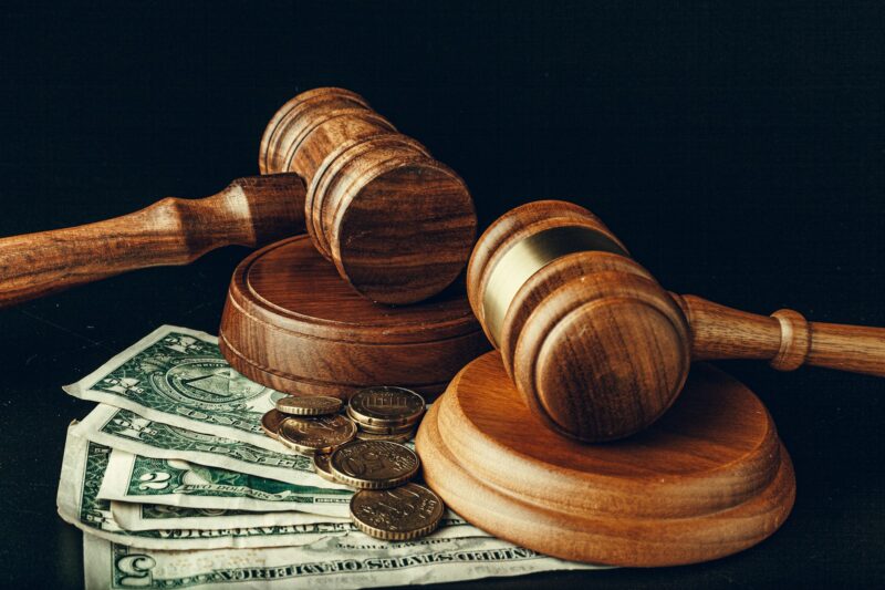 Wooden judge gavel on US dollar banknotes closeup. Justice corruption concept