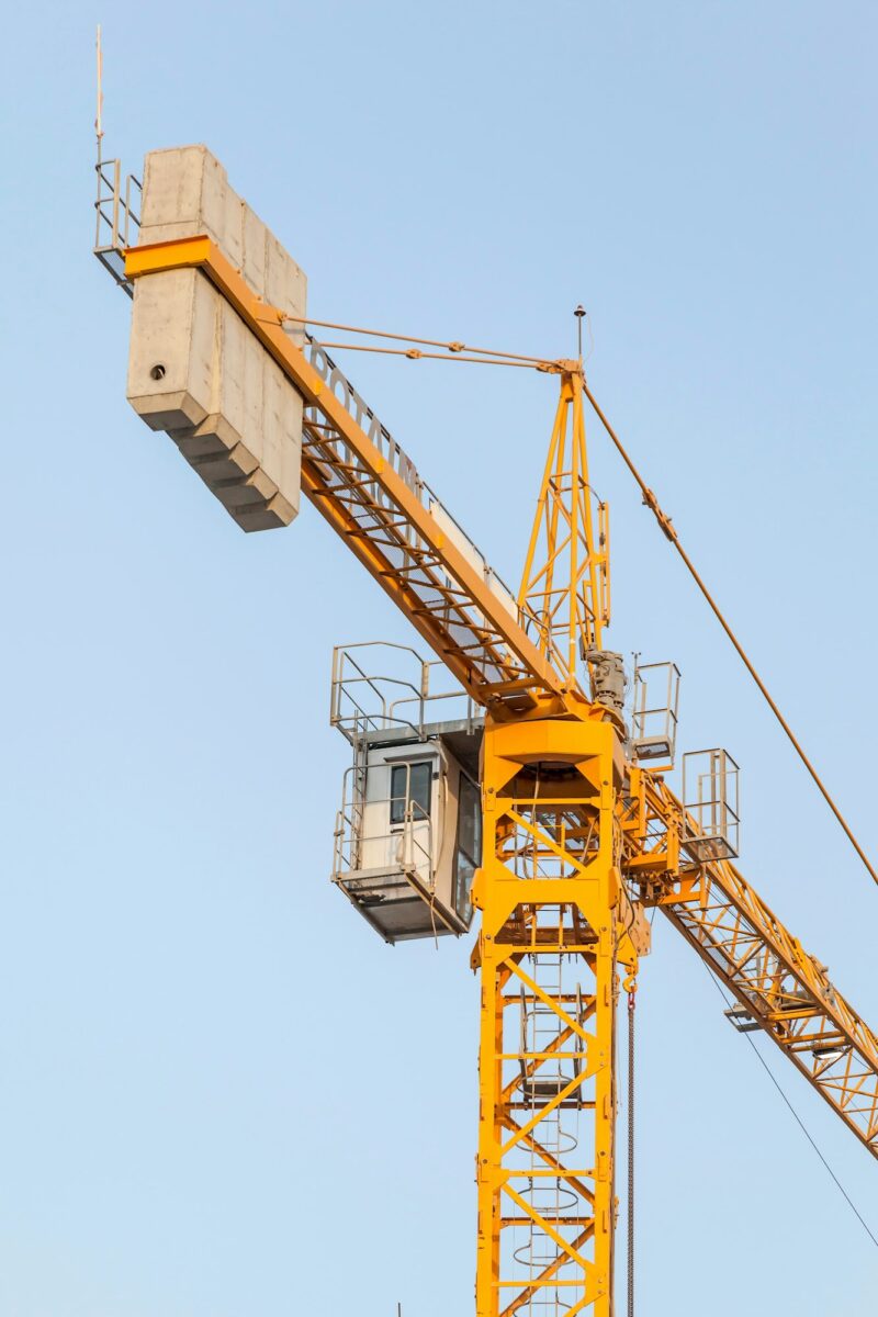 Yellow construction crane against the blue sky, infrastructure