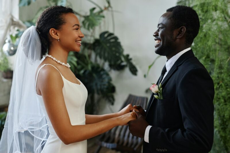 Young black couple as bride and groom looking at each other and holding hands