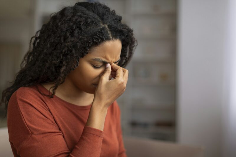 Young black woman feeling sinus pain, pressing on the nose bridge